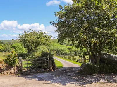 a fence and a tree on a dirt road at Sunbury Barn in St. Agnes