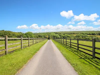 a dirt road in a field next to a fence at Sunbury Barn in St. Agnes