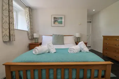 a bedroom with a large bed with towels on it at Sunbury Barn in St. Agnes