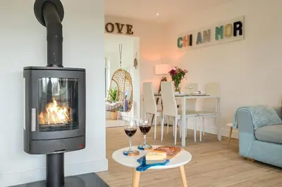 a living room with a fireplace and two glasses of wine at Chi An Mor in Newquay