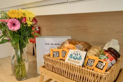 a basket of food on a table with a vase of flowers at Chi An Mor in Newquay