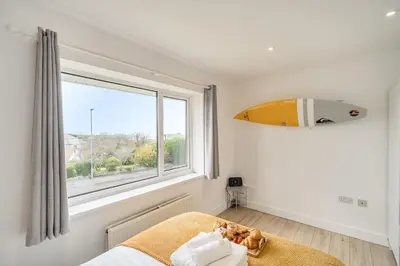 a bedroom with a bed and a window with a surfboard at Chi An Mor in Newquay