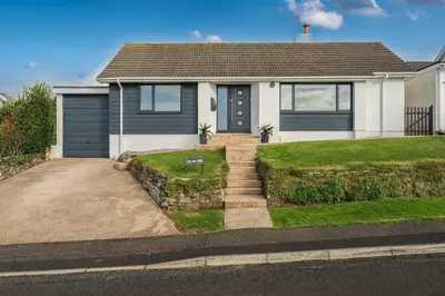 a white house with a blue door and a driveway at Chi An Mor in Newquay