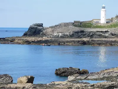 a lighthouse on a rocky shore next to the ocean at Trevow in Camborne