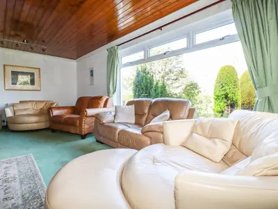 a living room with leather furniture and a large window at Trevow in Camborne