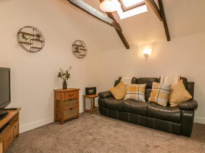 a living room with a leather couch and a tv at Little Prickle in Newquay