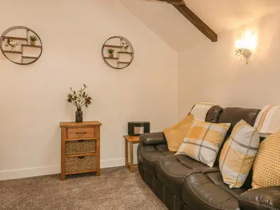a living room with a leather couch and two mirrors at Little Prickle in Newquay