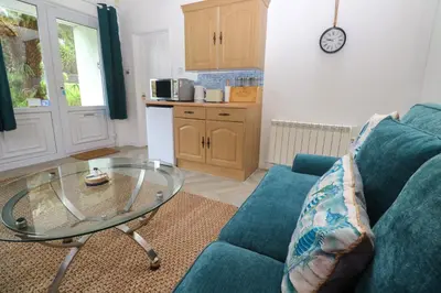 a living room with a blue couch and a glass table at Lighthouse in Penzance