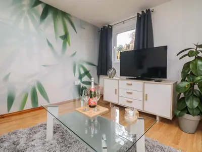 a living room with a glass table and a tv at Palm Lodge in Penzance