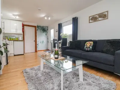 a living room with a black couch and a glass table at Palm Lodge in Penzance