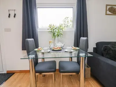 a living room with a glass table and chairs at Palm Lodge in Penzance