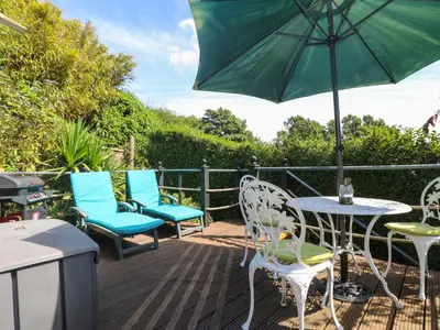 a patio with chairs and a table with an umbrella at Palm Lodge in Penzance