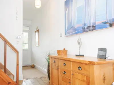 a room with a wooden dresser with a picture on the wall at Lowena Cottage in Looe