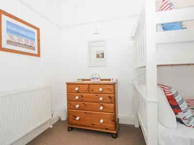 a bedroom with a bunk bed and a dresser at Lowena Cottage in Looe