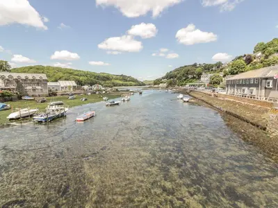 a river with boats in the water next to buildings at Lowena Cottage in Looe