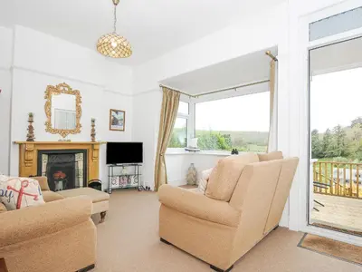 a living room with two chairs and a fireplace at Lowena Cottage in Looe