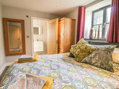 a bedroom with a large bed and a bathroom at The Coach House in Saint Columb Major