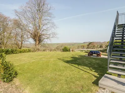 a park with a bench and a picnic table at The Coach House in Saint Columb Major
