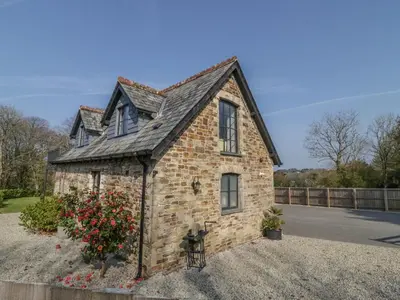 a small brick house with a black roof at The Coach House in Saint Columb Major