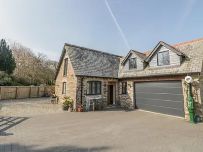 a brick house with a garage and a driveway at The Coach House in Saint Columb Major