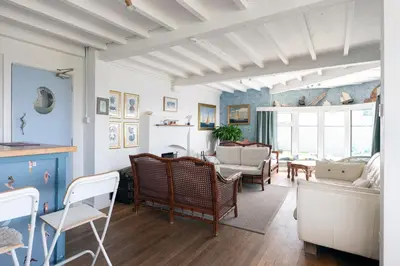 a living room with blue walls and a table and chairs at Blue Bay Beach House in Newquay
