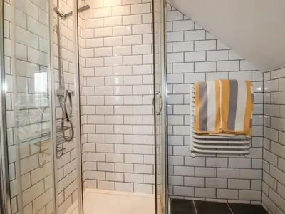 a bathroom with a shower and a towel at Blue Bay Beach House in Newquay