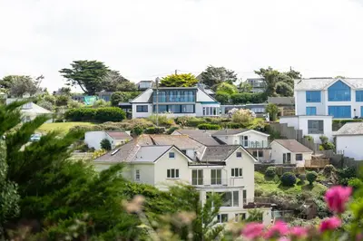 a group of houses on a hill with pink flowers at Blue Bay Beach House in Newquay
