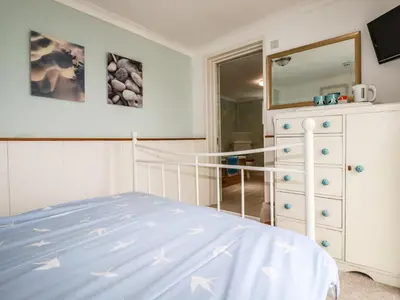 a bedroom with a bed and a dresser and a mirror at Blue Bay Beach House in Newquay