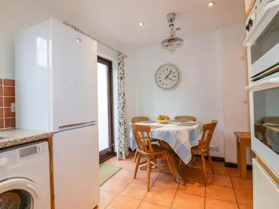 a kitchen with a table with chairs and a clock on the wall at Sarah's Cottage in Padstow