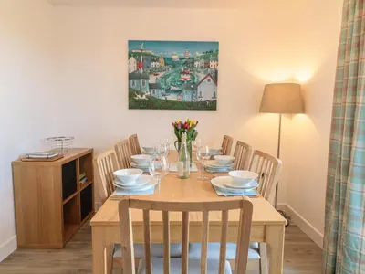 a dining room with a wooden table and chairs at Sea Dreams in Marazion