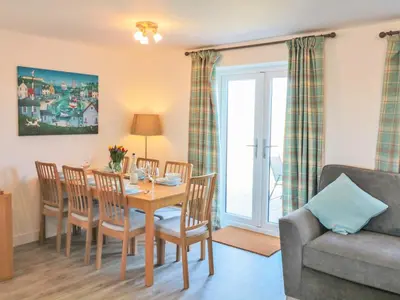 a dining room with a table and chairs and a couch at Sea Dreams in Marazion