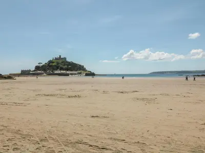 a sandy beach with a island in the distance at Sea Dreams in Marazion