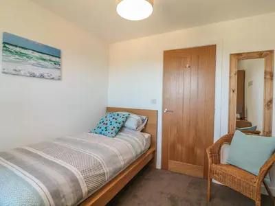 a bedroom with a bed and a chair at Ocean Breeze in Marazion
