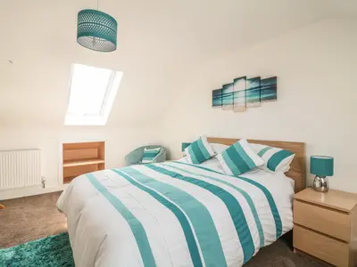 a bedroom with a bed with blue and white stripes at Ocean Breeze in Marazion