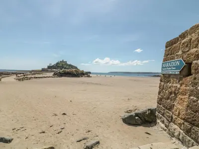 a sign on a beach with a castle in the background at Ocean Breeze in Marazion