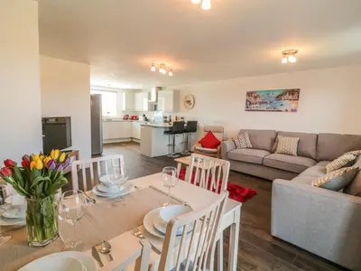 a kitchen and living room with a table and a couch at Ocean Breeze in Marazion