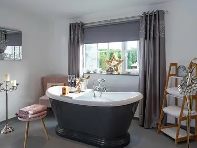 a bathroom with a bath tub and a window at Be Our Guest Cottage in Truro