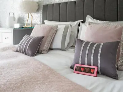 a bed with a bunch of pillows and a pink box ofocolates at Be Our Guest Cottage in Truro