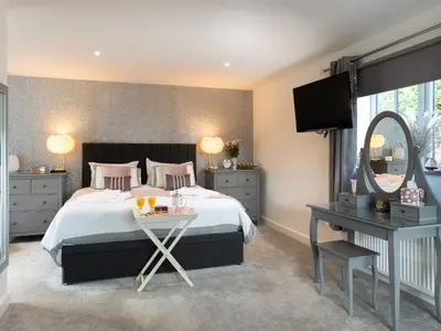 a bedroom with a bed with a mirror and a table at Be Our Guest Cottage in Truro