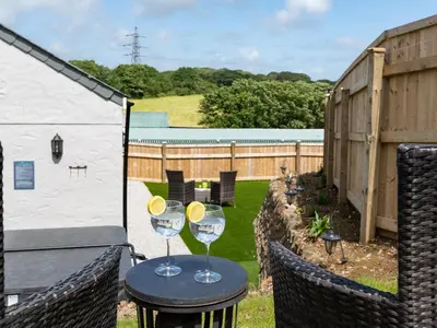 two wine glasses on a table in a backyard at Be Our Guest Cottage in Truro