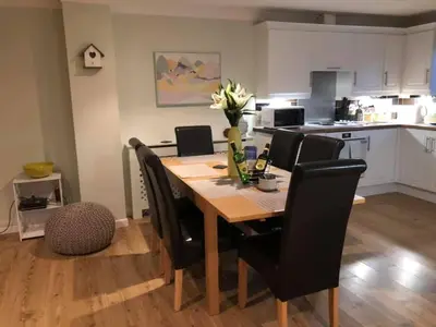 a dining room table with black chairs and a kitchen at Atlantic Lodge in Newquay