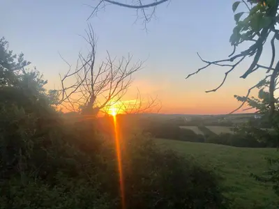a sunset over a field with the sun setting at Atlantic Lodge in Newquay