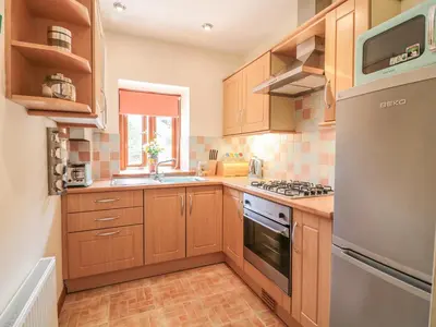 a kitchen with wooden cabinets and a stove top oven at Woodside Barns in St Austell
