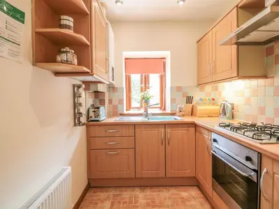 a kitchen with wooden cabinets and a sink at Woodside Barns in St Austell