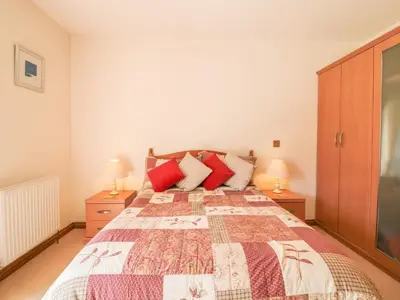 a bedroom with a large bed with red pillows at Woodside Barns in St Austell