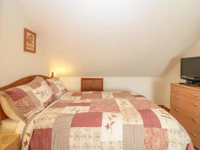a bedroom with a bed and a dresser with a tv at Woodside Barns in St Austell