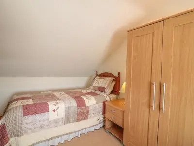 a bedroom with a bed and a wooden cabinet at Woodside Barns in St Austell