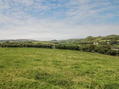 a field of grass with hills in the background at Woodside Barns in St Austell