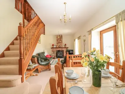 a living room with a table and a staircase at Woodside Barns in St Austell