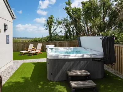 a hot tub in a yard with two stools at Bear Cottage in Truro